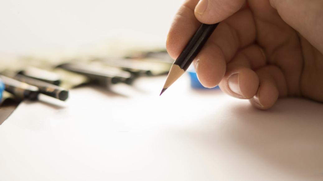 A hand holding a pencil while sketching group designed to create and heal