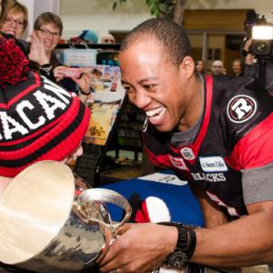 Henry Burris holding the Grey Cup with a client at The Royal